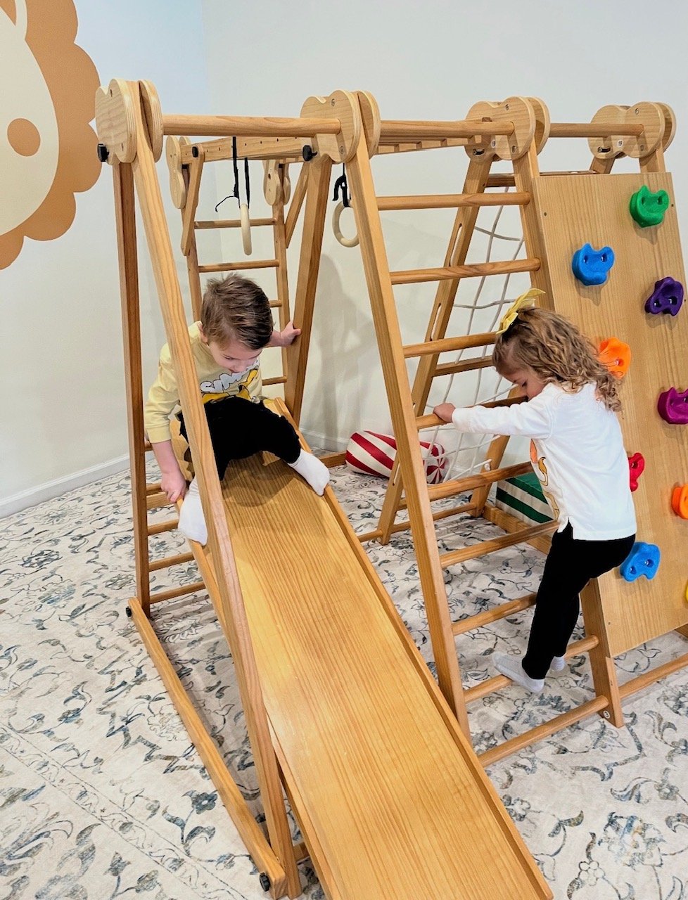 Children playing on the indoor wooden slide and climbing frame